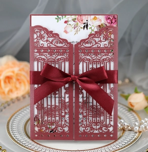 Laser-cut burgundy wedding invitation with elegant ribbon bow and floral inner card