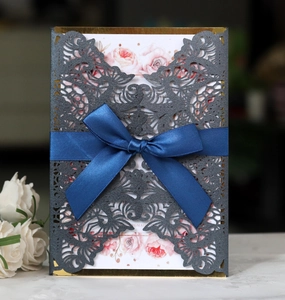 Detail of laser-cut hollow card with dark blue satin bow and floral inner page