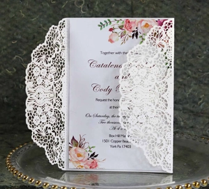 Detailed laser-cut white lace wedding invitation with elegant floral print insert card