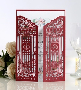 Detail of red laser-cut wedding invitation with elegant gate design and floral inner card