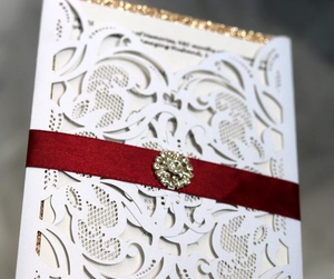 Détail de l'invitation découpée au laser avec ruban bordeaux et strass étincelants