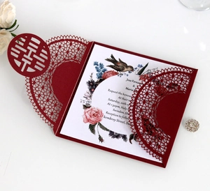 Detail of laser-cut burgundy wedding invitation with Xi character and floral inner card
