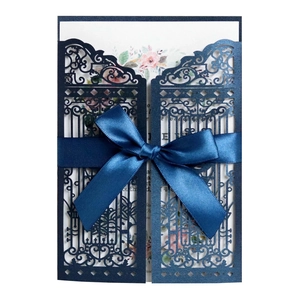 Detail of laser-cut navy blue wedding invitation with ribbon and floral insert