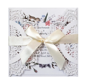 Close-up of laser cut lavender wedding invitation with a satin bow and floral inner sheet