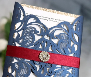 Détail de l'invitation découpée au laser avec ruban satin rouge et boucle en strass