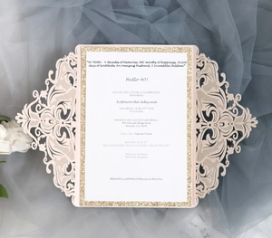 Macro shot of laser-cut lace invitation with gold glitter border and pink hollow cover
