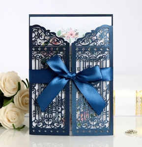 Detail of laser-cut navy wedding invitation with satin bow and floral inner card