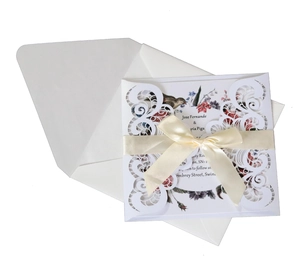 Elegant white laser-cut lace invitation card with a cream silk ribbon and floral insert