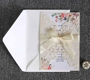 Detailed laser-cut wedding invitation set with lace pocket, floral card and beige ribbon