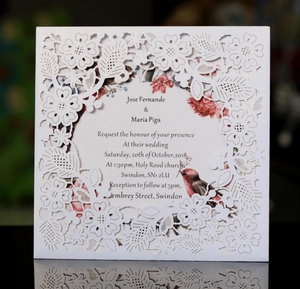 Détail macro de l'invitation de mariage découpée au laser avec motifs floraux blancs