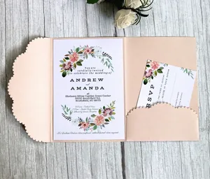 Elegant laser-cut floral wedding invitation set with pearl pink envelope on wood background