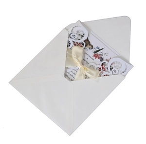 Elegant laser-cut white lace wedding invitation with floral inner card and ribbon