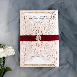 Détail de l'invitation de mariage découpée au laser avec papier perlé et ruban rouge