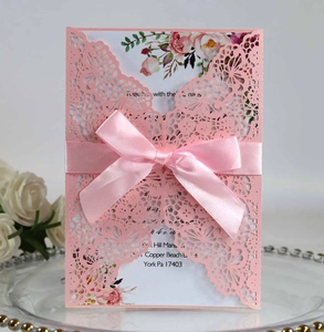 Detailed laser-cut hollow pink wedding invitation with a silk ribbon and floral insert