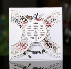 Macro shot of laser-cut wedding invitation featuring intricate lace patterns and Xi character