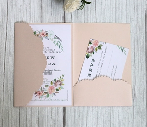 Pink laser-cut wedding invitation set with floral watercolor cards on grey wood background