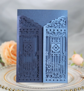 Detail of laser-cut navy blue invitation cover with intricate European gate patterns