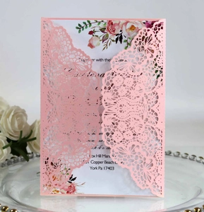 Detail view of laser-cut pink wedding invitation with lace floral patterns and inner card