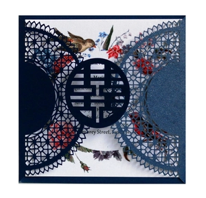 Detail of laser-cut Xi character and intricate mandala patterns on navy wedding invitation