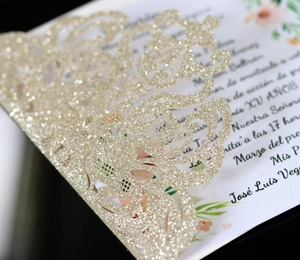 Detailed close-up of golden glitter laser-cut invitation with intricate floral patterns