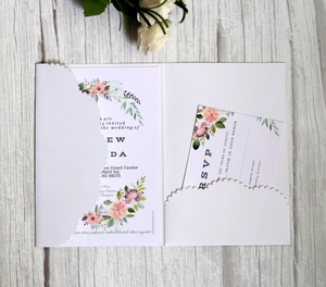 Detail of laser-cut floral wedding invitation with RSVP card on a wooden surface