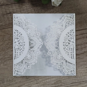 Macro detail of laser cut hollow wedding invitation with intricate lace on wooden background