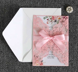 Detail of pink laser-cut lace wedding invitation set with elegant satin ribbon bow