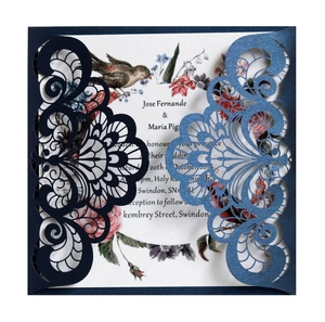 Macro view of laser-cut navy blue hollow floral wedding invitation with bird pattern
