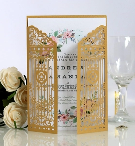 Close-up of laser-cut golden wedding invitation sleeve with floral inner card