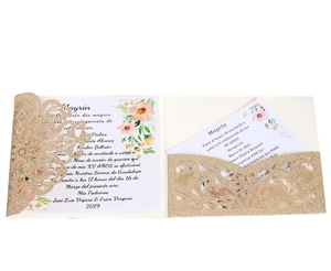 Close-up of laser cut gold glitter invitation cover with floral printed insert card
