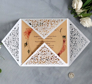 Elegant white laser cut wedding invitation set with floral patterns on rustic kraft paper