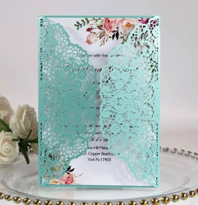 Intricate laser-cut lace wedding invitation with floral insert on elegant tray