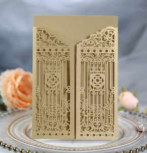 Close-up of golden laser-cut wedding invitation featuring elegant gate pattern on a plate