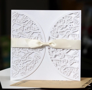 Detail of laser-cut butterfly wedding invitation with cream satin ribbon and kraft insert