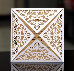 Detailed laser-cut scrollwork on premium white wedding invitation with kraft insert