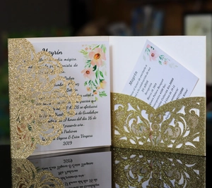 Close-up of laser-cut gold glitter wedding invitation with floral inner card details