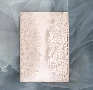 Macro shot of laser-cut rose patterns on a light pink pearlescent invitation cover