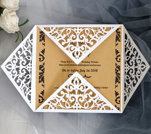Detail of laser-cut wedding invitation cover with intricate floral lace and kraft paper insert