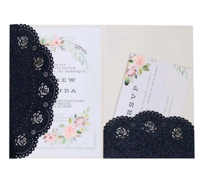 Close-up of laser-cut wedding invitation with navy glitter paper and floral details