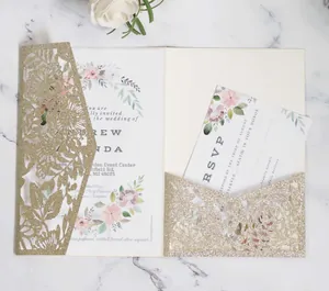 Macro shot of gold glitter laser-cut invitation with floral card and RSVP on marble