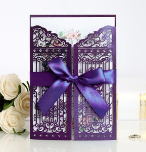 Macro detail of laser-cut purple wedding invitation with silk bow and floral insert