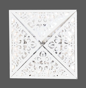 Detail of laser-cut white wedding invitation featuring intricate floral lace patterns