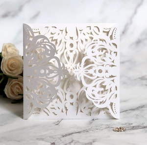Close-up of white laser-cut wedding invitation with intricate lace floral patterns