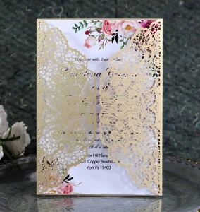 Detail of laser-cut lace wedding invitation with gold finish and floral inner card