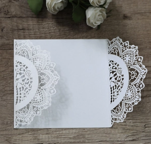 Detail of laser-cut white lace wedding invitation with glitter texture on wooden surface