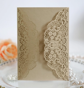 Detailed laser-cut lace pattern on kraft paper wedding invitation card on glass tray