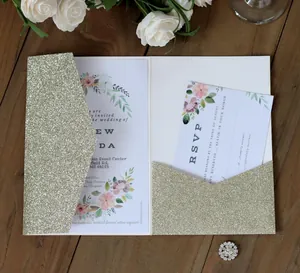Elegant gold glitter hollow wedding invitation set with floral cards on dark wood background