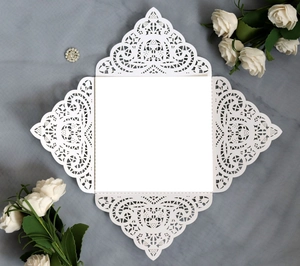 Detail of laser-cut pearl paper wedding invitation with white floral lace pattern