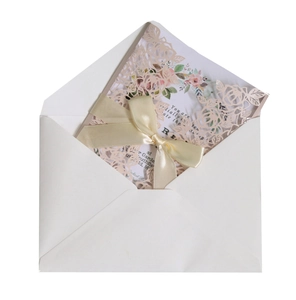 Pink laser-cut invitation card with floral inner sheet and cream ribbon on envelope