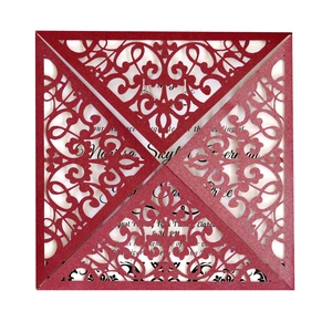 Detail of red laser-cut wedding invitation with lace patterns and glitter finish